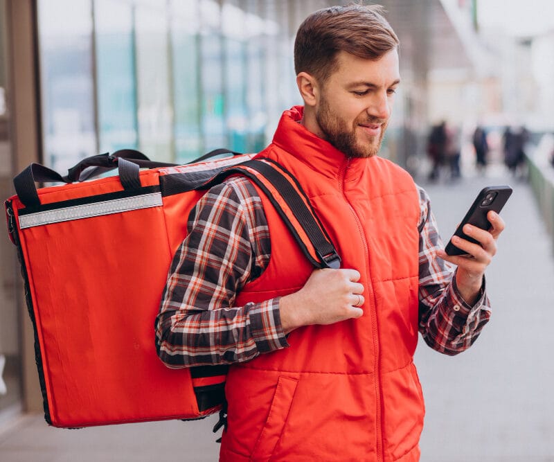 Food delivery driver with insulated delivery bag promoting restaurant webshop alternative to Uber Eats and DoorDash in Canada