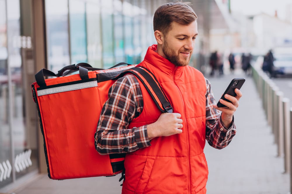 Food delivery driver with insulated delivery bag promoting restaurant webshop alternative to Uber Eats and DoorDash in Canada